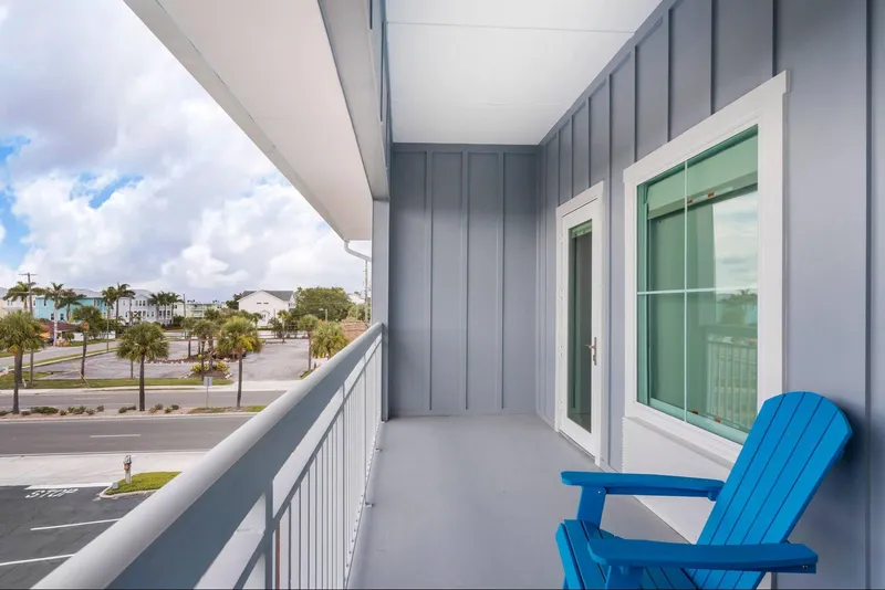 A blue Adirondack chair on a guest balcony looking out at palm trees
