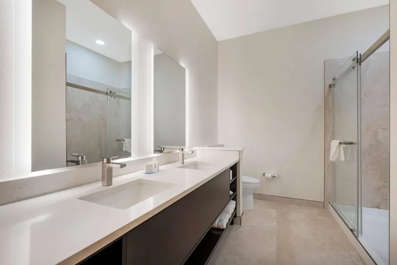 Bathroom with lit mirrors and a glass shower