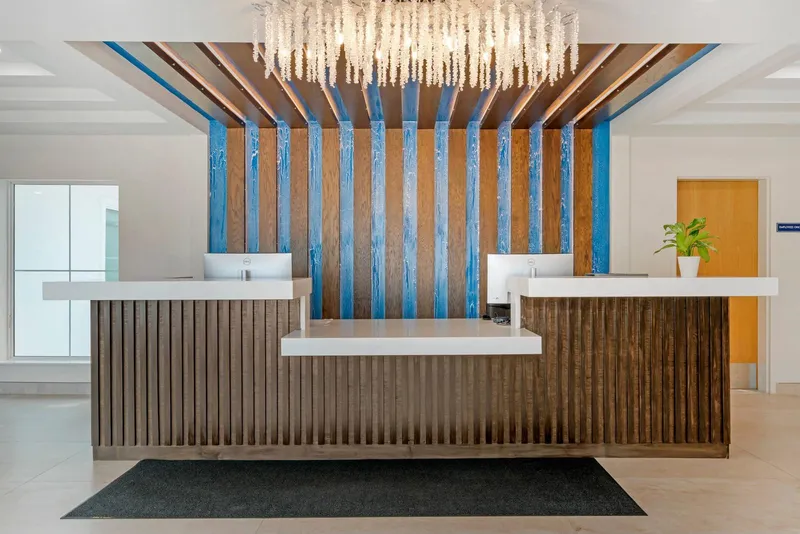 Lobby front desk with blue and wood slat wall and chandelier