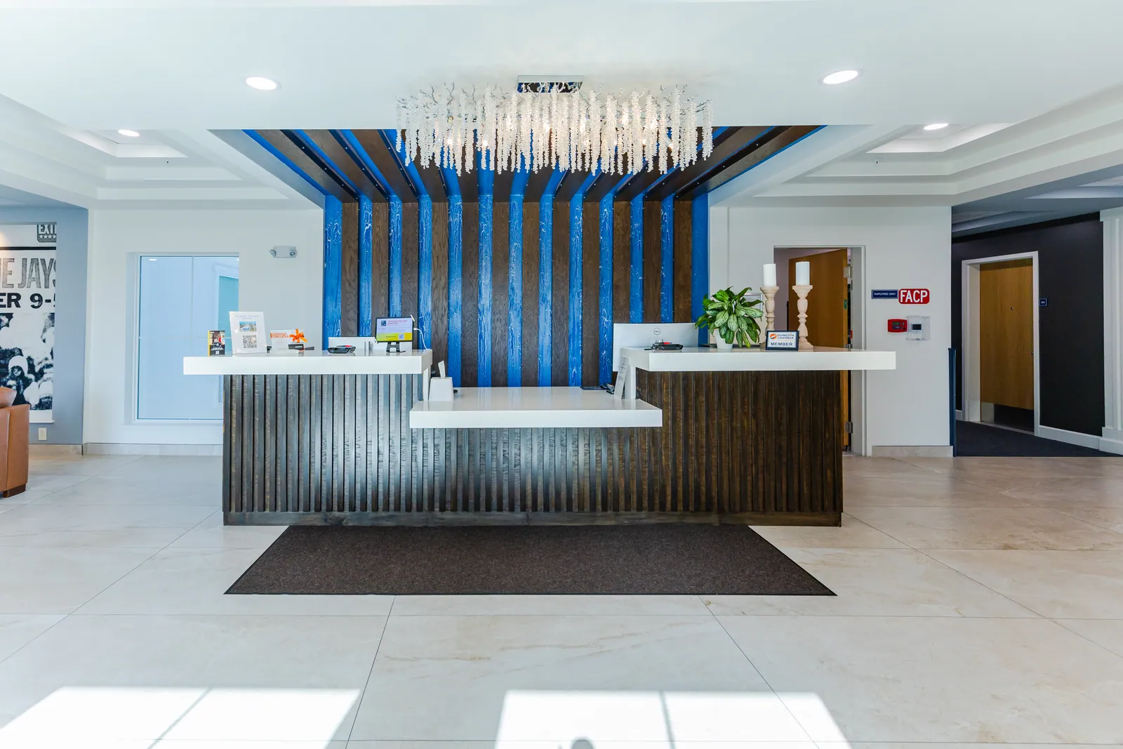 The J Hotel front desk with a blue and wood slat wall and a crystal chandelier