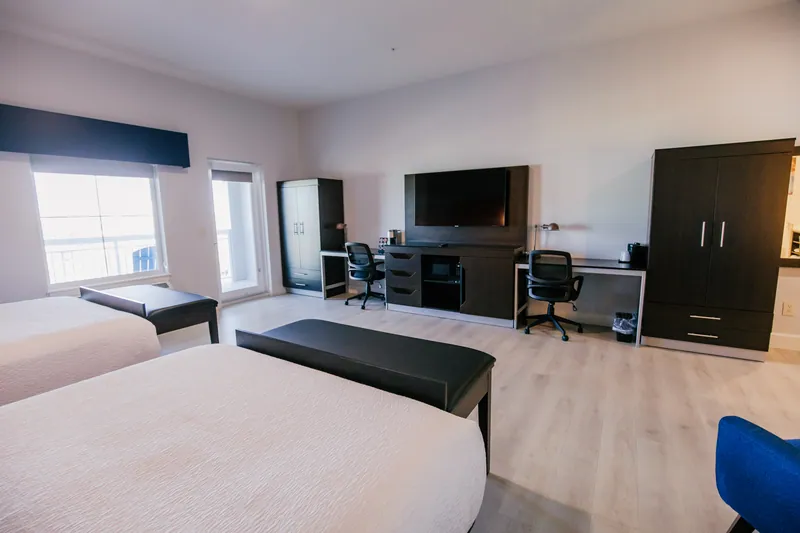 Guest room with two beds, a desk, TV and wardrobe
