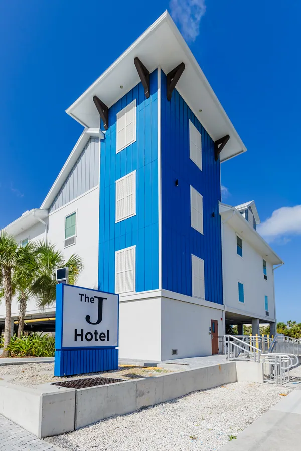 The J Hotel's blue tower and sign against a blue sky