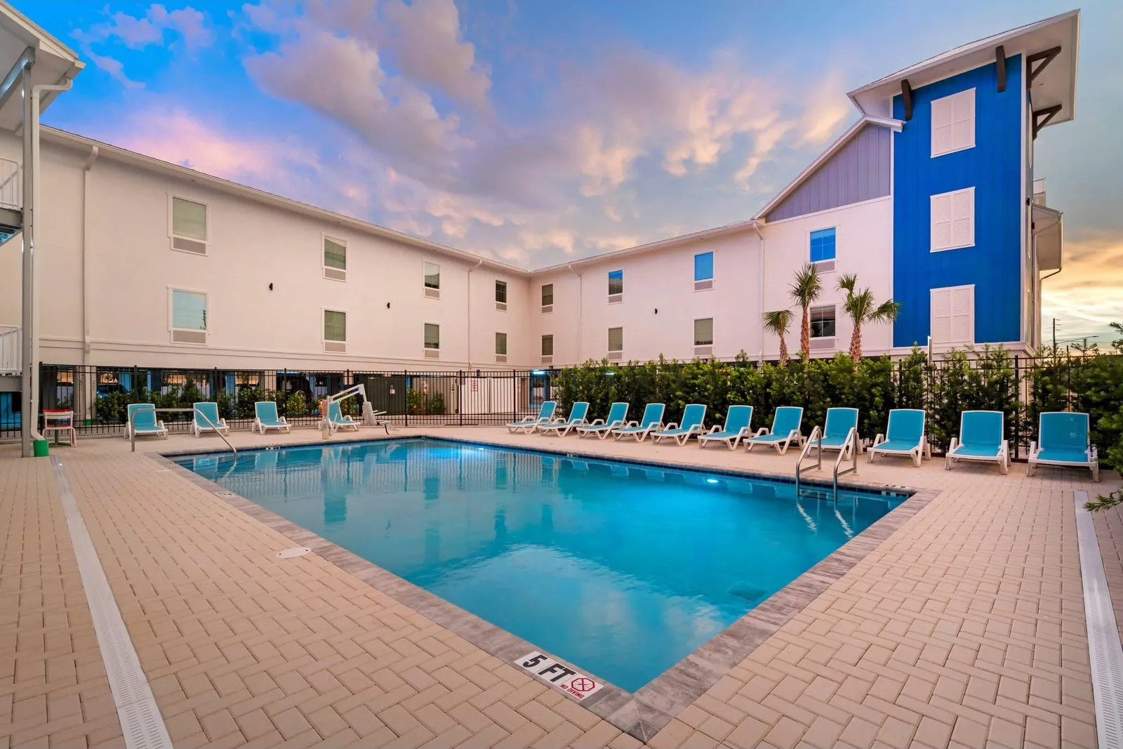 The heated outdoor pool at dusk with blue lounge chairs and the hotel's blue tower
