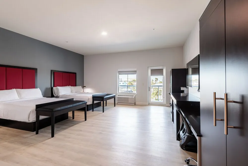 Guest room with two queen beds, wood floors and a door out to the balcony