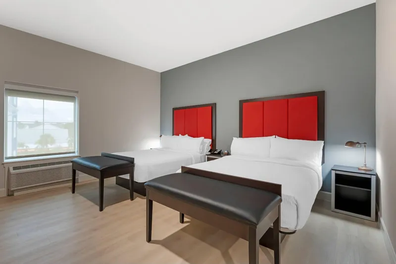 Two queen room with red headboards and a window